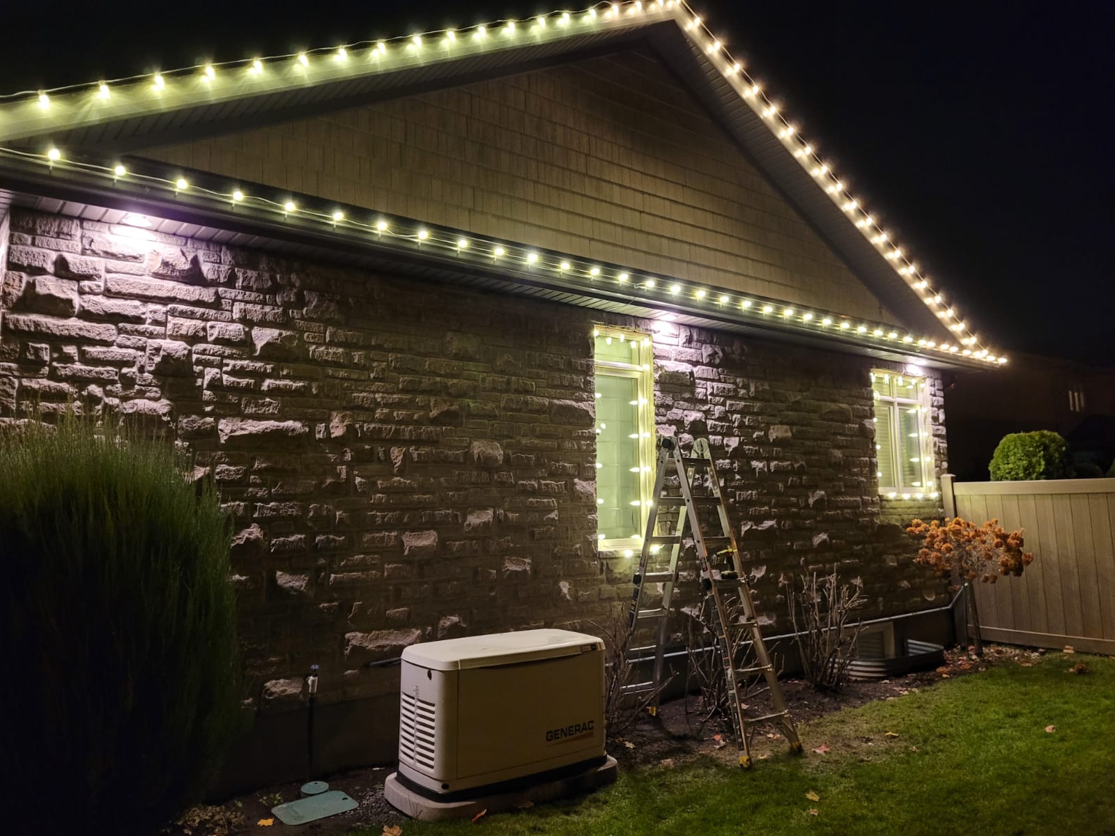 Window-frame wraps and warm-white roofline on a stone home
