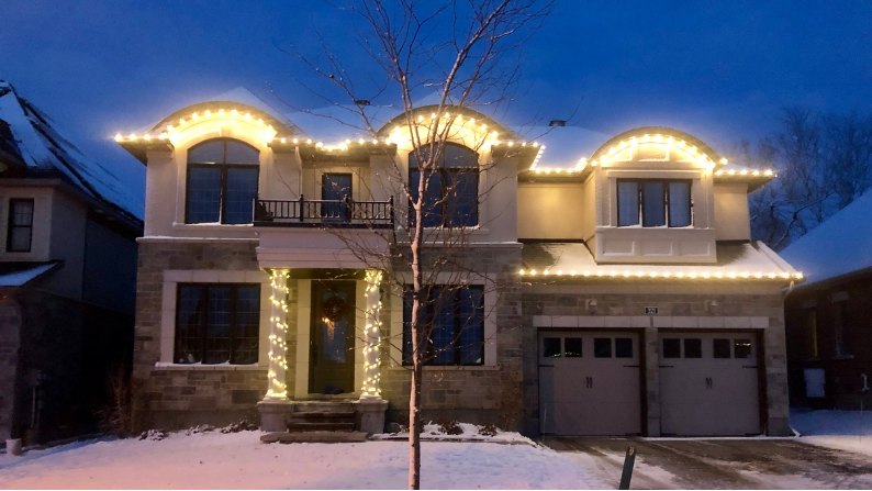 Warm-white roofline and wrapped entry pillars at dusk